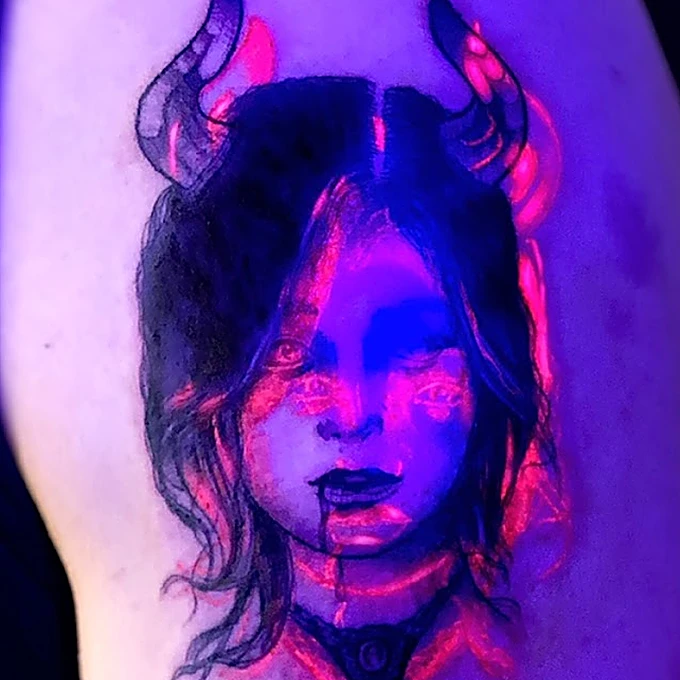 Paso 3, bajo luz UV: el brazo se ve violeta y los trazos reactivos brillan en rosa intenso.